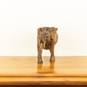 Close up of hand-carved Balinese elephant showing dark natural wood grain lines and upward trunk.