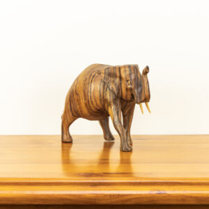 Close up of hand-carved Balinese elephant showing dark natural wood grain lines and upward trunk.
