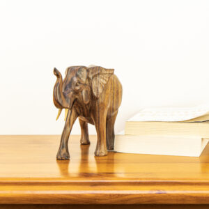 Close up of hand-carved Balinese elephant showing dark natural wood grain lines and upward trunk.