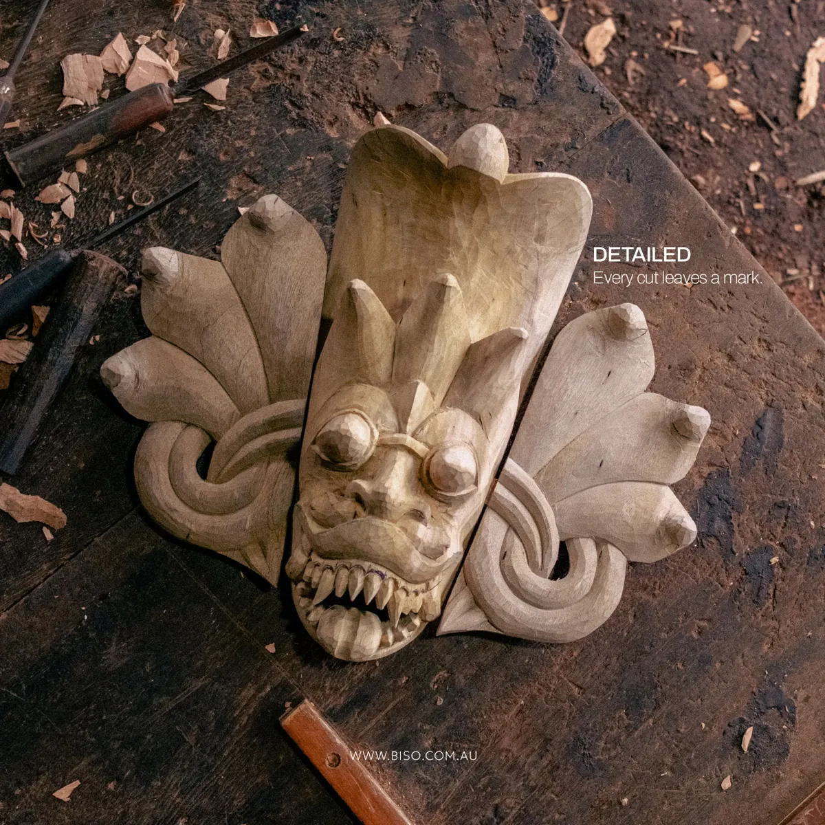 Unpainted hand-carved Naga Raksha cobra mask with coiled snake side panels on a wooden workbench – authentic Sri Lankan wood work